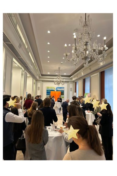 Ein hoher Besucheransturm Gruppen von Menschen stehen in einem eleganten Raum mit Tischen und Kunstwerk im Hintergrund.
